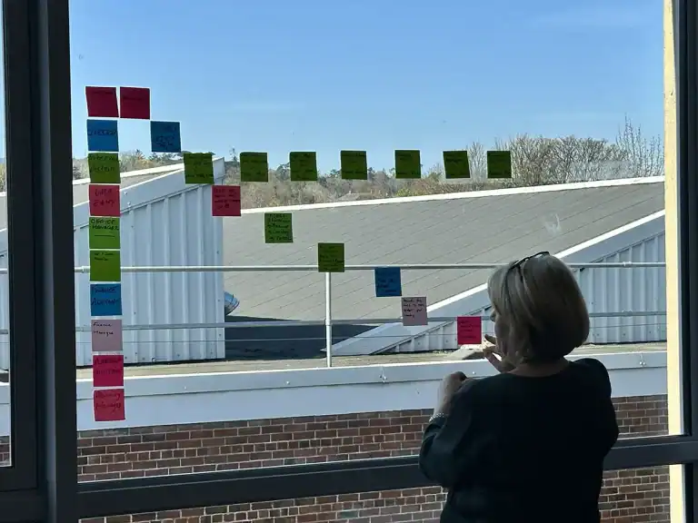 Person reviewing a Kanban board with sticky notes for operational excellence.