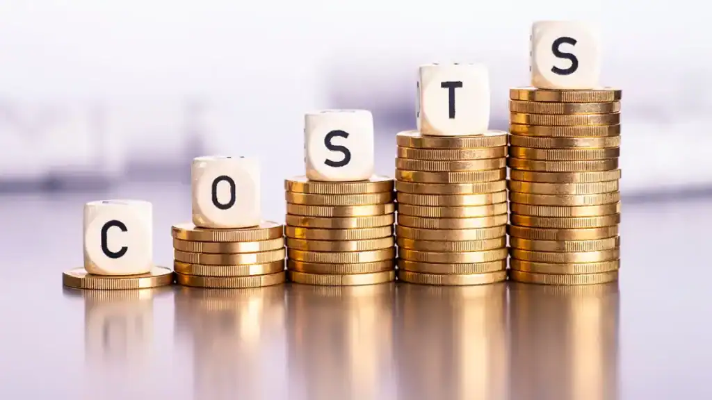 Stacks of coins with letter blocks spelling COST.
