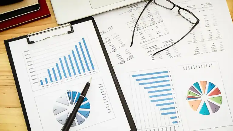 Financial charts and glasses on a desk for business analysis.