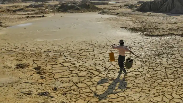 Person walking on cracked dry land in a drought-affected area in Ireland.