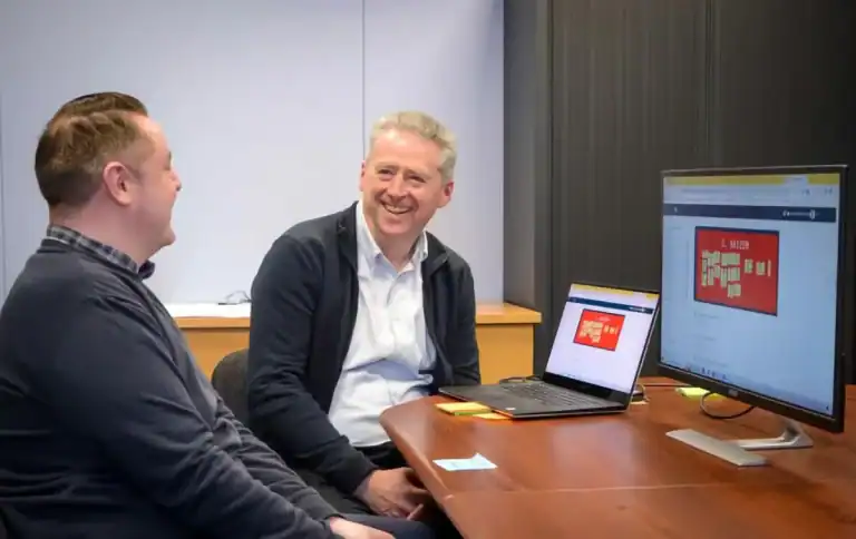 Two men in a business meeting discussing Lean training and operational excellence.