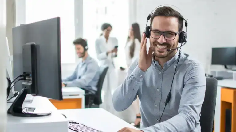 Happy customer support agent with headset in modern office environment.