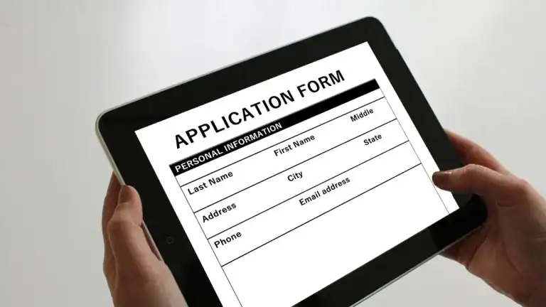 Person holding a tablet displaying a form for application or registration.