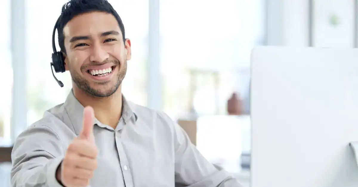 Customer support representative with headset giving thumbs up.