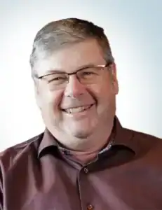 Smiling man with glasses in a professional setting.